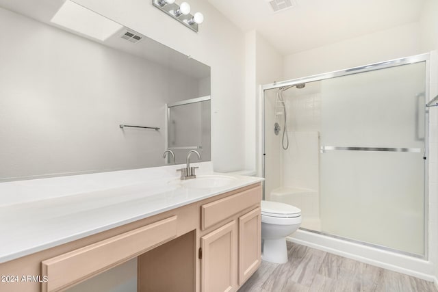 bathroom with wood-type flooring, a shower with door, toilet, and vanity