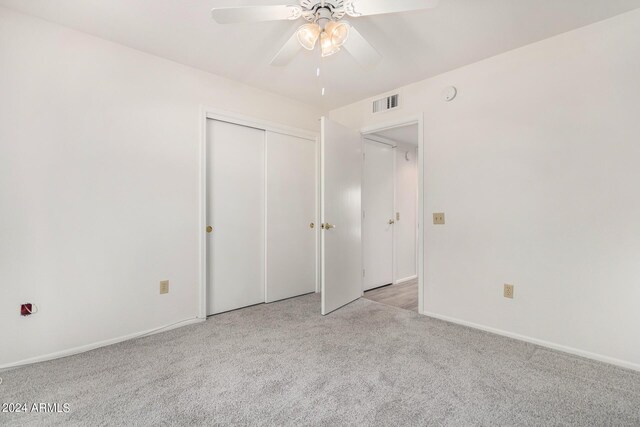 unfurnished bedroom featuring ceiling fan, light colored carpet, and a closet