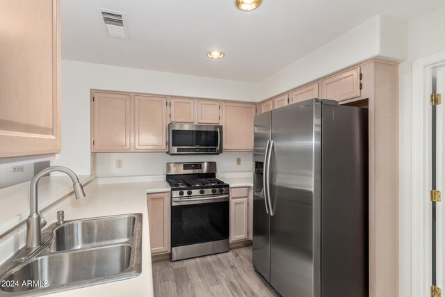 kitchen featuring appliances with stainless steel finishes, light brown cabinetry, and sink