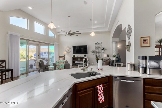 kitchen featuring dishwasher, open floor plan, a sink, arched walkways, and a ceiling fan