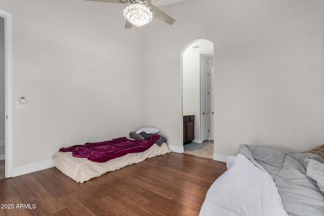 bedroom featuring arched walkways, wood finished floors, baseboards, and a ceiling fan