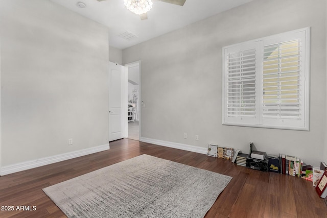 empty room featuring dark wood-type flooring, baseboards, and a chandelier