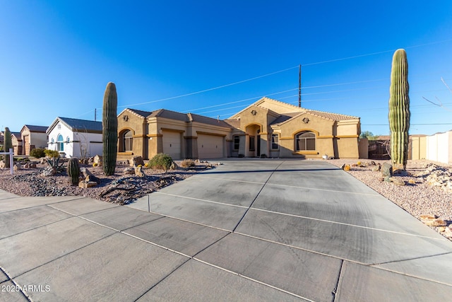 mediterranean / spanish home featuring stucco siding, an attached garage, driveway, and fence