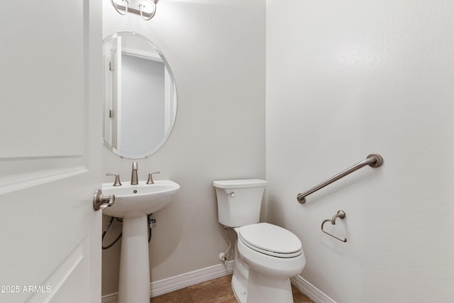 half bath with baseboards, toilet, and tile patterned flooring