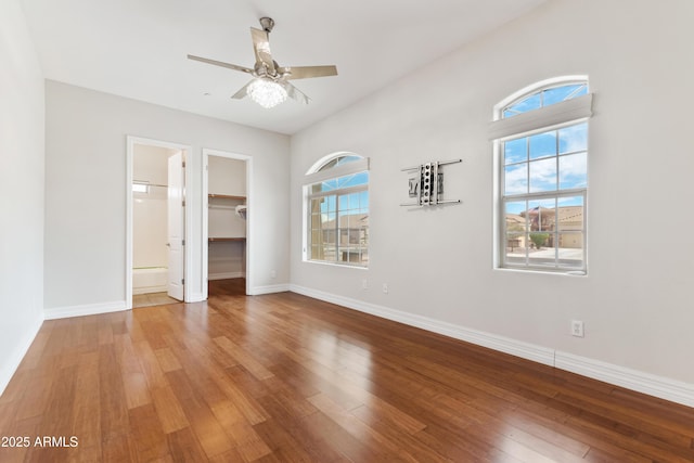 unfurnished bedroom with hardwood / wood-style flooring, baseboards, and a spacious closet