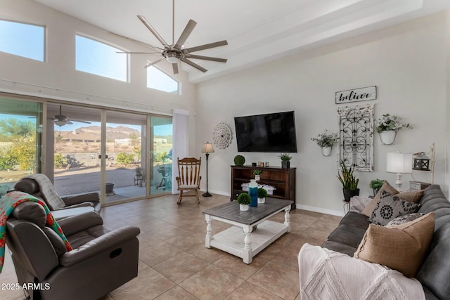 living area featuring ceiling fan, light tile patterned flooring, a high ceiling, and baseboards