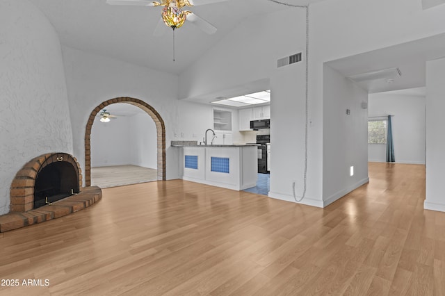 2916 S Revere Cir, Mesa, AZ 85210 - unfurnished living room with ceiling fan, high vaulted ceiling, light wood-type flooring, a sink, and a fireplace