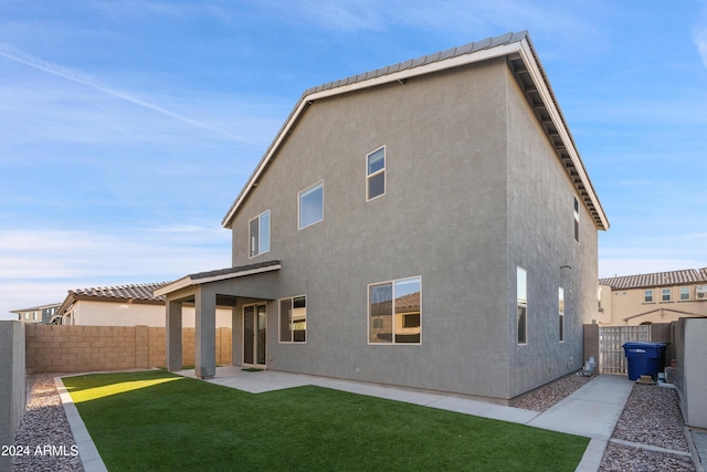 back of property with a lawn and a patio area