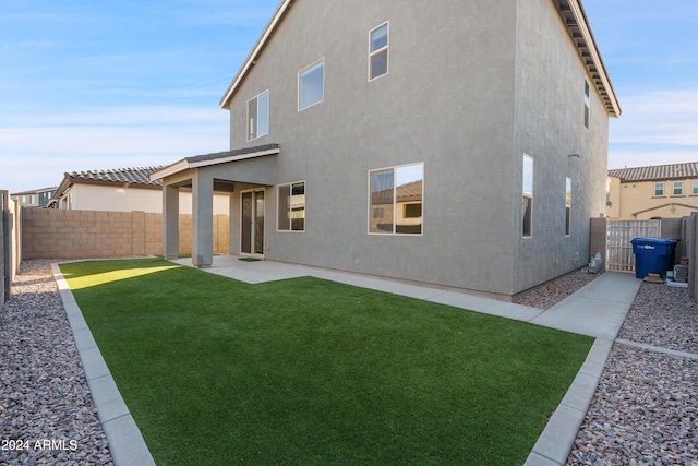 back of house with a lawn and a patio