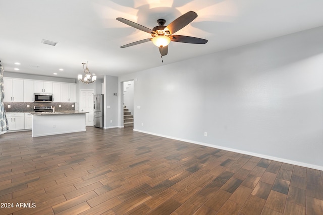 unfurnished living room with dark hardwood / wood-style flooring and ceiling fan with notable chandelier