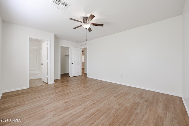 unfurnished bedroom with ceiling fan, light hardwood / wood-style flooring, a spacious closet, a closet, and ensuite bath