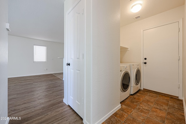 clothes washing area with washing machine and clothes dryer and dark wood-type flooring