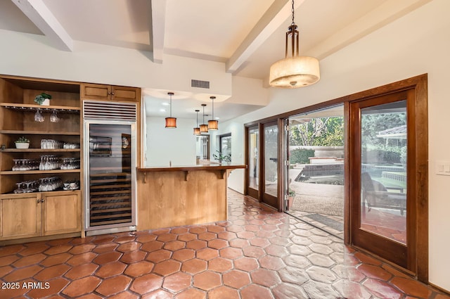 kitchen with beam ceiling, a kitchen breakfast bar, wine cooler, decorative light fixtures, and kitchen peninsula