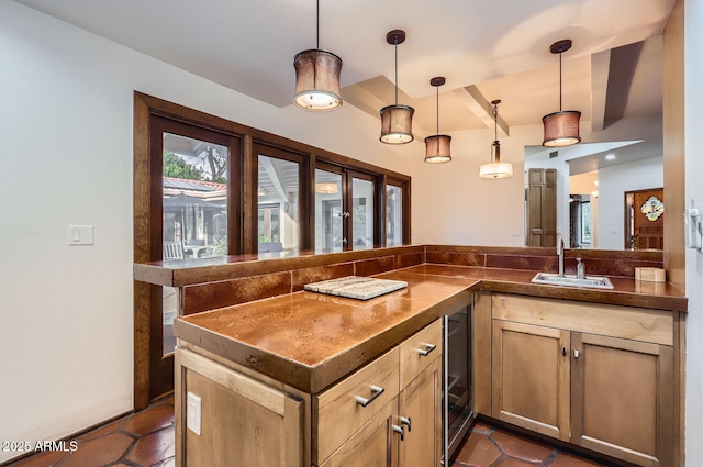 kitchen featuring sink, kitchen peninsula, wine cooler, and decorative light fixtures