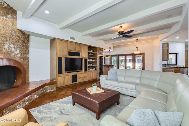 living room featuring sink, beam ceiling, dark tile patterned floors, ceiling fan, and a fireplace