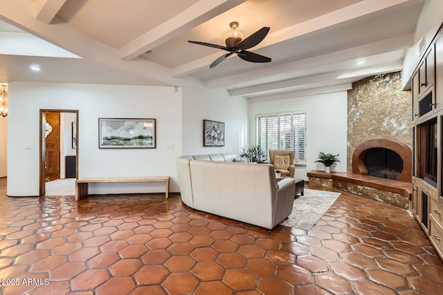 living room featuring beamed ceiling, a large fireplace, and ceiling fan