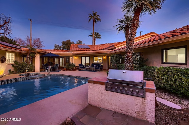 pool at dusk with a grill, area for grilling, an in ground hot tub, and a patio