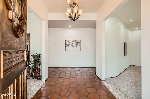 hall with a chandelier and dark colored carpet