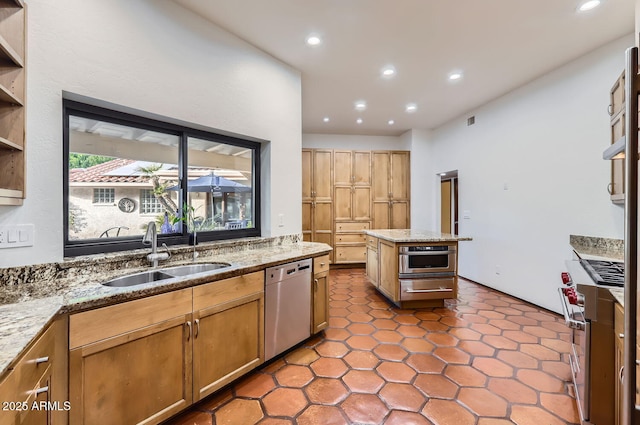 kitchen featuring light stone counters, stainless steel appliances, sink, and a kitchen island