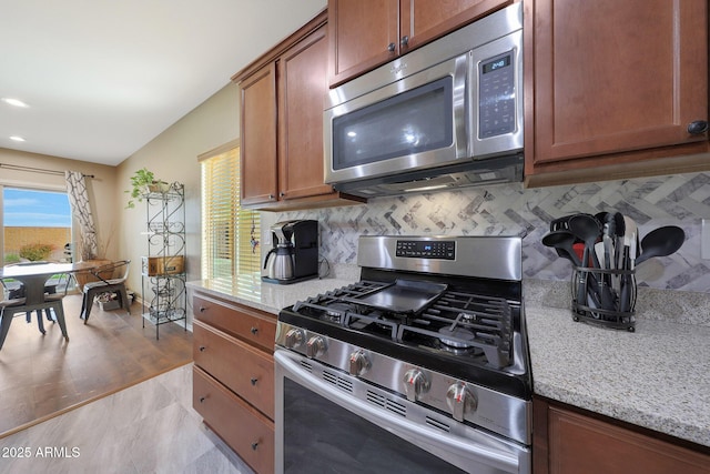 kitchen featuring tasteful backsplash, light stone countertops, and appliances with stainless steel finishes