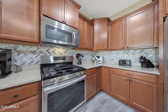 kitchen featuring light stone counters, stainless steel appliances, and backsplash