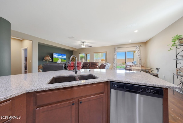 kitchen featuring ceiling fan, stainless steel dishwasher, light stone countertops, and sink