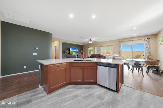 kitchen featuring sink, stainless steel dishwasher, light hardwood / wood-style floors, and a center island with sink