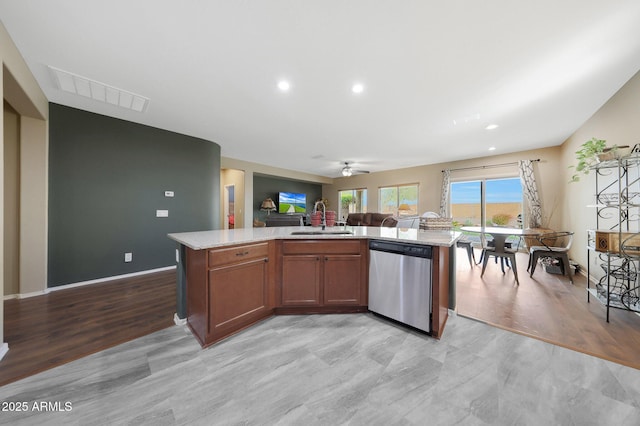 kitchen with sink, dishwasher, light stone countertops, light hardwood / wood-style floors, and a center island with sink