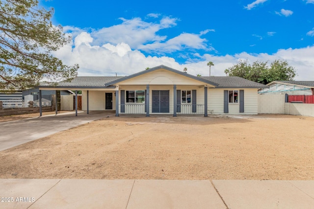 ranch-style house featuring covered porch, driveway, an attached carport, and fence