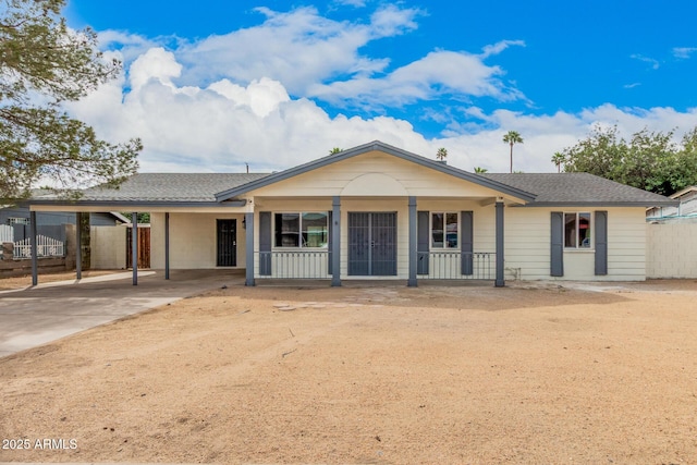 single story home with an attached carport, a porch, a shingled roof, fence, and driveway