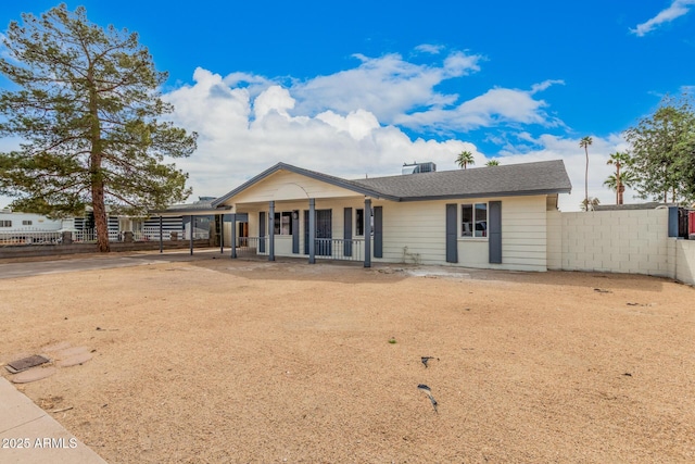 view of front of home with driveway, fence, a carport, and roof with shingles