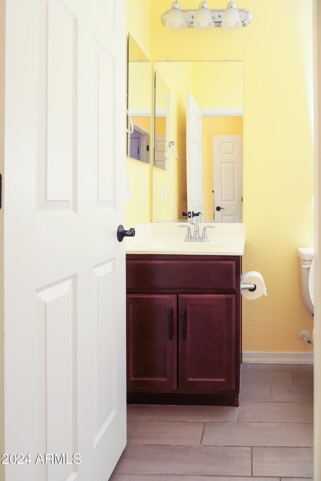 bathroom with wood-type flooring, vanity, and toilet