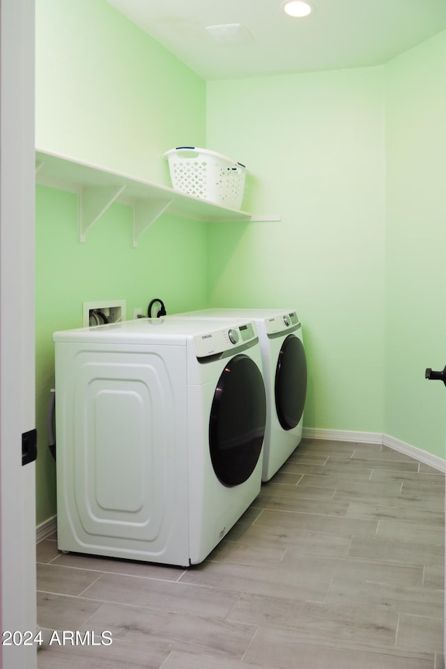 clothes washing area with separate washer and dryer and light hardwood / wood-style floors