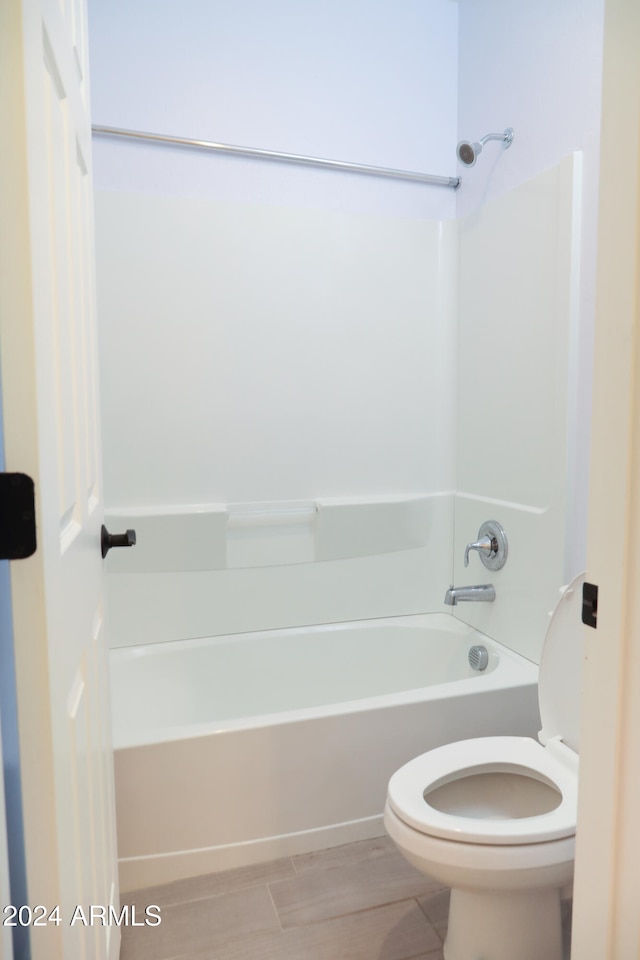 bathroom with shower / bathtub combination, toilet, and wood-type flooring