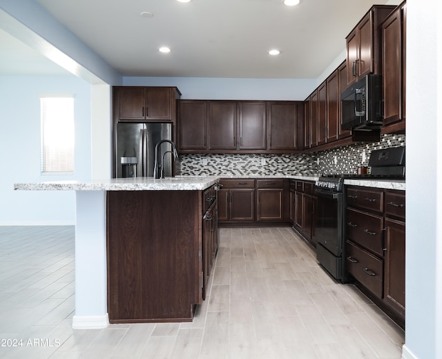 kitchen featuring decorative backsplash, dark brown cabinetry, a kitchen island with sink, and black appliances