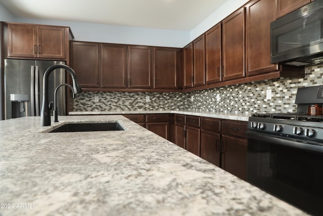 kitchen featuring tasteful backsplash, stainless steel fridge, sink, and black range with gas cooktop