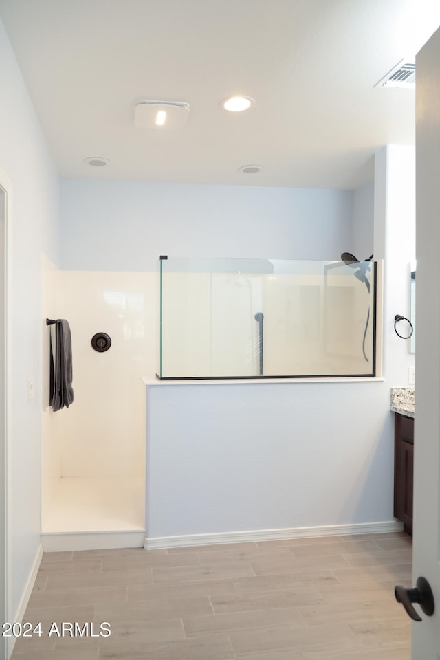 bathroom featuring vanity, a shower, and wood-type flooring