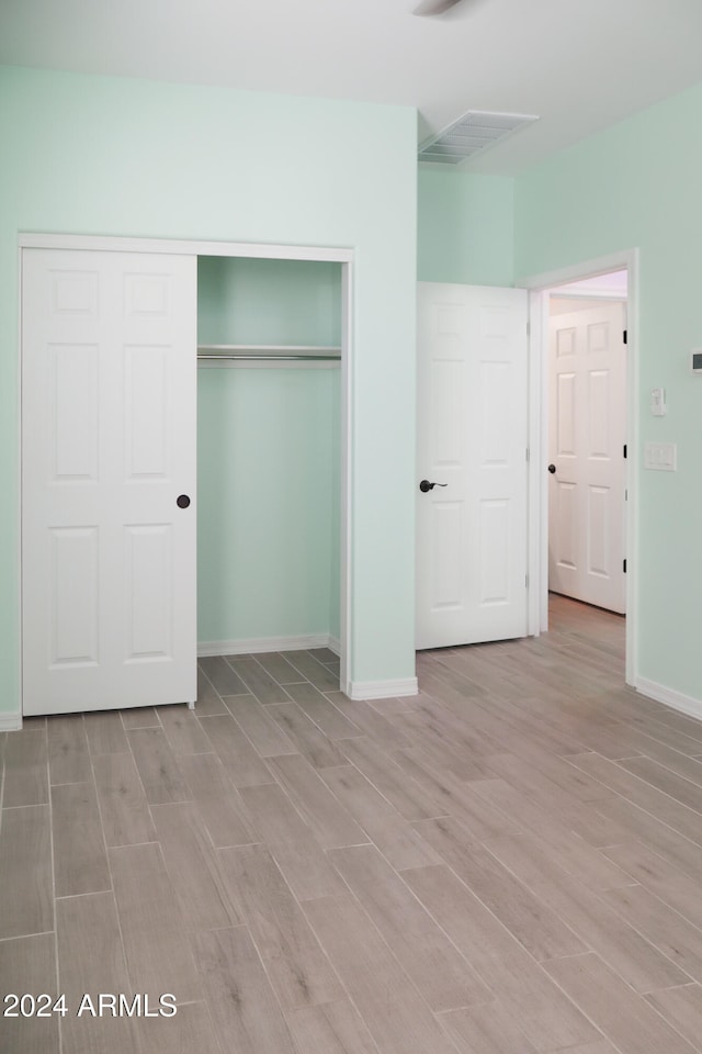 unfurnished bedroom featuring a closet and light wood-type flooring