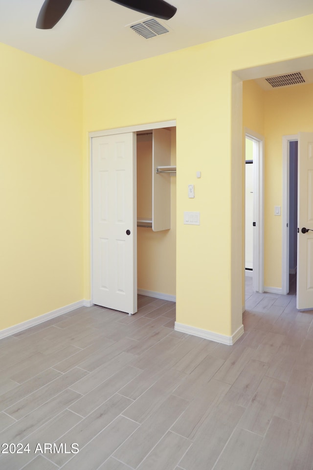 unfurnished bedroom with ceiling fan, a closet, and light hardwood / wood-style floors