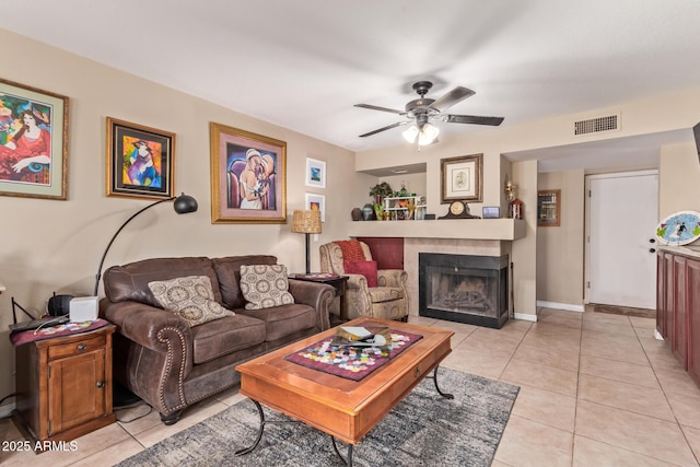 tiled living room with ceiling fan and a fireplace