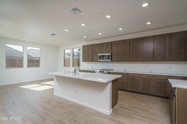 kitchen with light hardwood / wood-style flooring, sink, a center island with sink, and appliances with stainless steel finishes