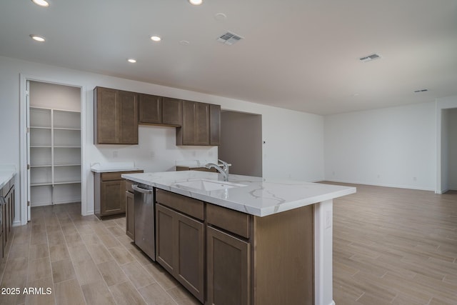 kitchen featuring sink, light hardwood / wood-style flooring, light stone countertops, and an island with sink