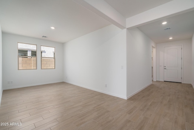 unfurnished room featuring beamed ceiling and light hardwood / wood-style floors