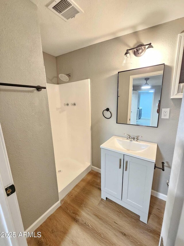 4520 N 28th Dr, Phoenix, AZ 85017 - full bath with wood finished floors, walk in shower, vanity, a textured wall, and baseboards