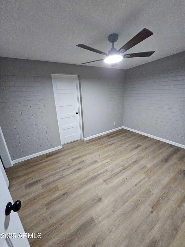 4520 N 28th Dr, Phoenix, AZ 85017 - unfurnished bedroom featuring baseboards, wood finished floors, a textured ceiling, brick wall, and a ceiling fan