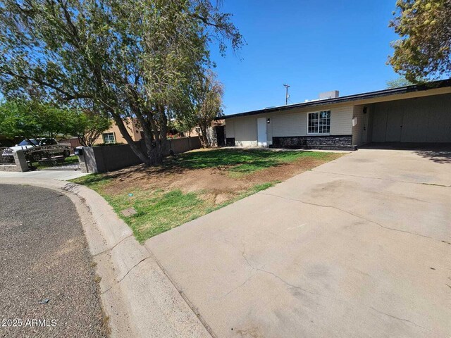 4520 N 28th Dr, Phoenix, AZ 85017 - view of front of home featuring fence, driveway, stone siding, and a carport