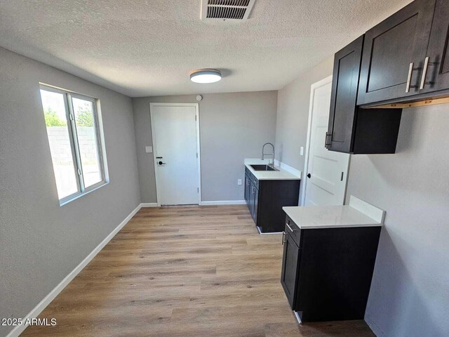 4520 N 28th Dr, Phoenix, AZ 85017 - kitchen featuring a sink, light countertops, light wood-style floors, a textured ceiling, and baseboards