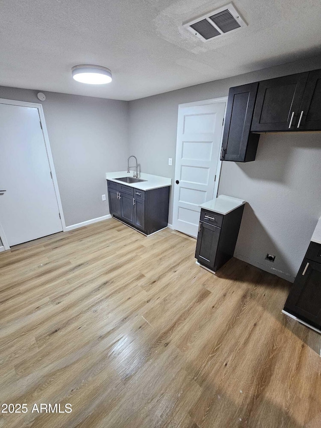4520 N 28th Dr, Phoenix, AZ 85017 - kitchen featuring a sink, light wood finished floors, light countertops, a textured ceiling, and baseboards