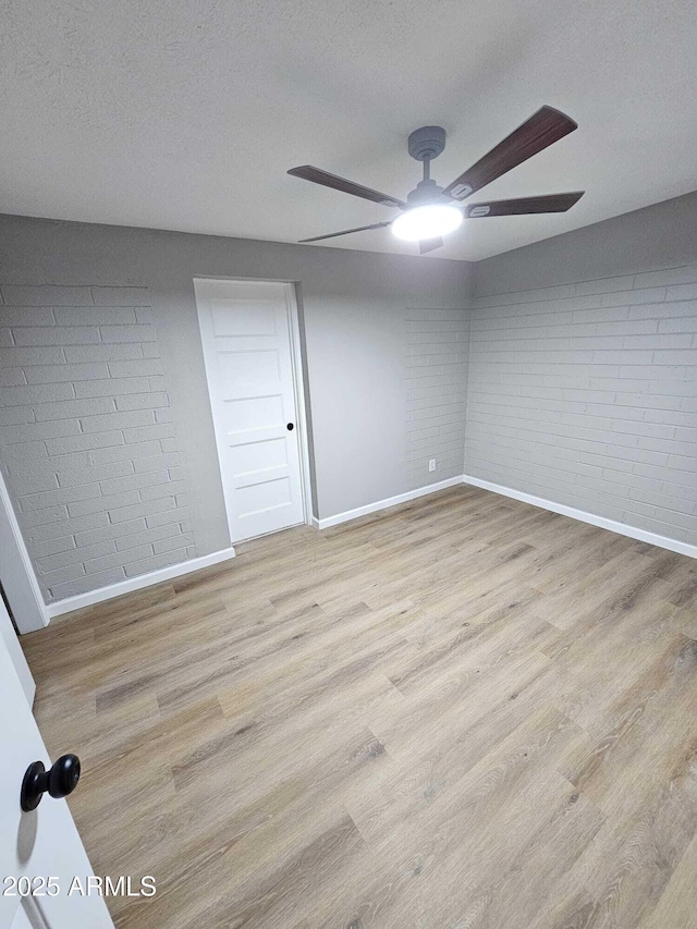 4520 N 28th Dr, Phoenix, AZ 85017 - spare room featuring baseboards, a ceiling fan, brick wall, wood finished floors, and a textured ceiling