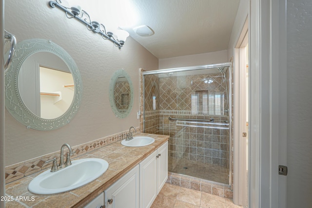 bathroom with a shower with shower door, a textured ceiling, vanity, and tile patterned flooring